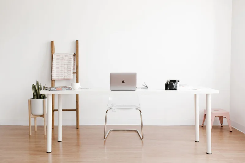 A naturally lit desk with a laptop and plants